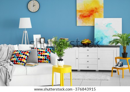 Living room interior with white furniture and green plants and pictures on blue wall background