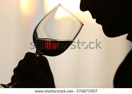 Silhouette of man sniffing red wine in a glass, close up