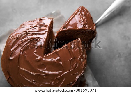 Chocolate cake with a cut piece and blade on gray background, closeup