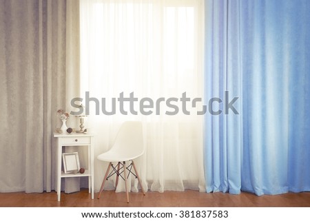 Small white table with lamp and chair on curtain background