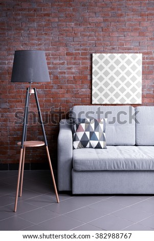 Grey sofa and floor lamp against brick wall in the room