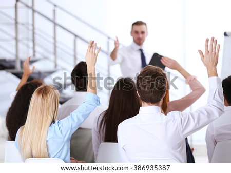 Young colleagues raising hands at the business meeting in office