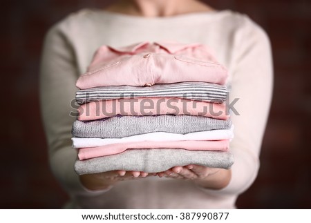 Woman holding washed and dried clothes on brick wall background