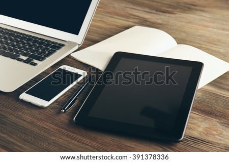 Modern laptop, tablet, mobile phone and notebook on the table, close-up