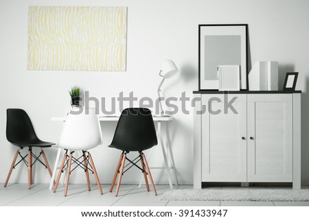Room interior with commode, frames, chairs and table on white wall background