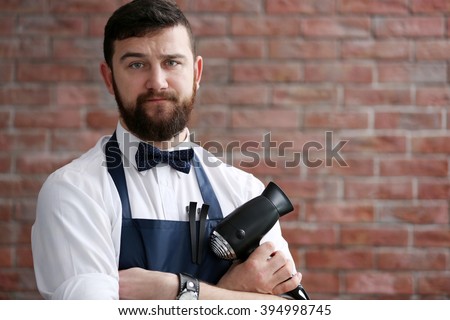 Professional hairdresser with accessories on brick wall background