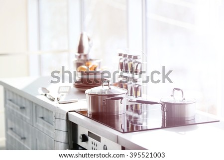 Modern electric stove with utensils in the kitchen beside window