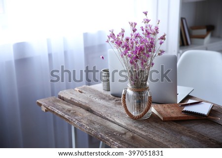 Modern interior. Comfortable workplace. Wooden table with beautiful bouquet of flowers and laptop on it, close up