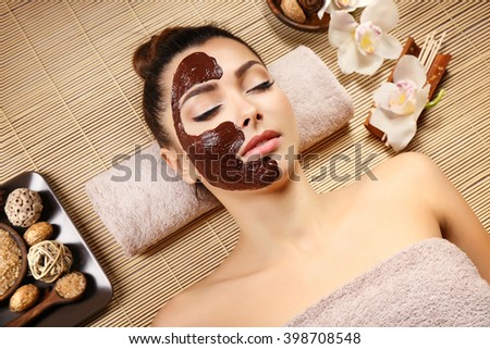 Beautiful young girl lying with chocolate mask in spa salon