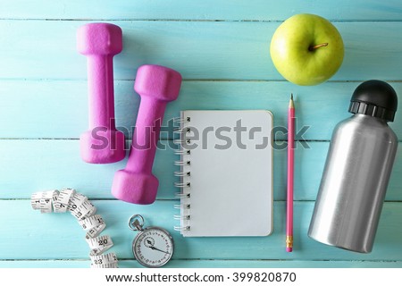 Athlete\'s set with equipment, notebook and bottle of water and apple on blue wooden background
