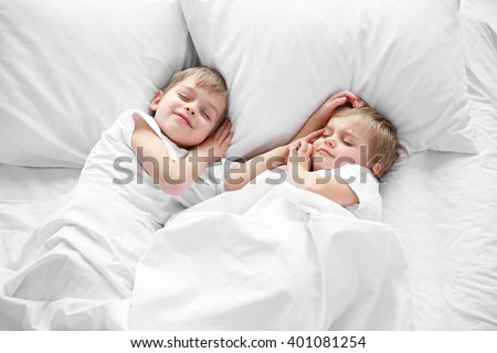 Cute boys sleeping in bed under blanket, closeup