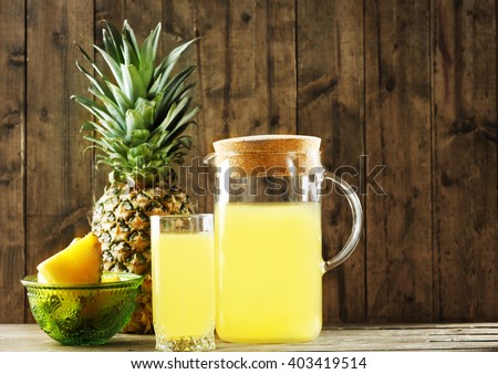Pineapple slices and juice in glassware on wooden table