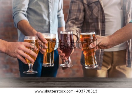 Male group clinking glasses of dark and light beer at the table