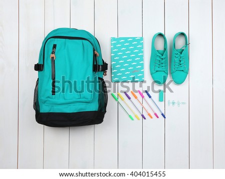 Backpack and school supplies on wooden background, close up. Top view.