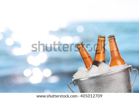 Beer bottles of cold fresh beer in ice bucket, on sea or ocean background