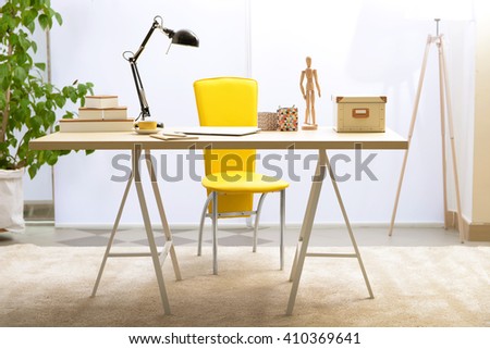 Workplace with table, yellow chair and laptop in living room