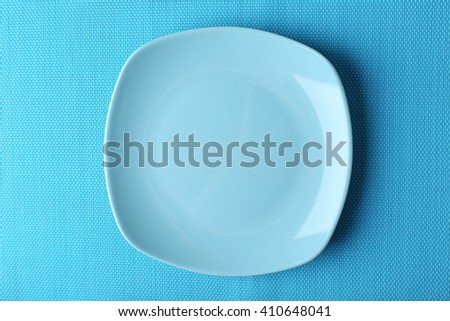 Empty plate on blue textured mat background