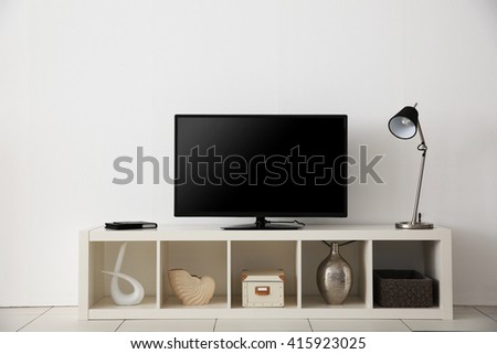 wide screen TV on white stand near light wall