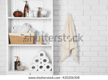 Bathroom set with towels, toothbrushes and basket on a shelf in light interior