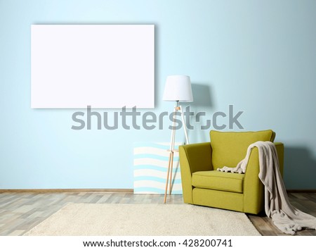 Room interior with green armchair and empty picture frame on blue wall background
