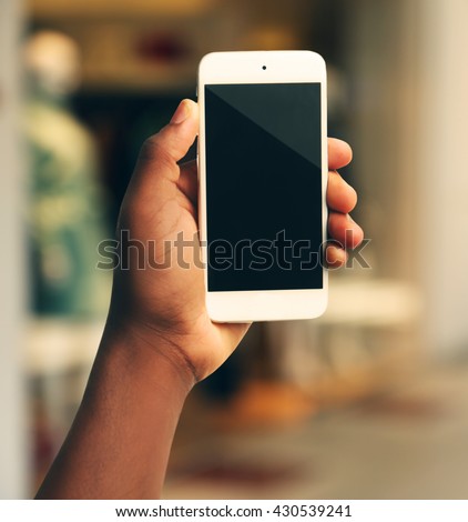 Mans hand shows mobile smart phone, blurred background