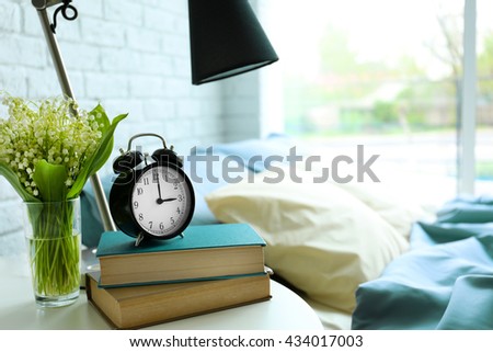 Lamp, books and flower bouquet on a side table
