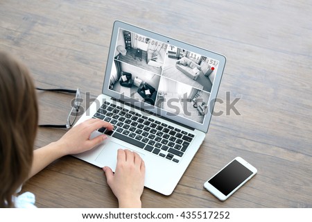 Woman using laptop at the table. Home security system concept