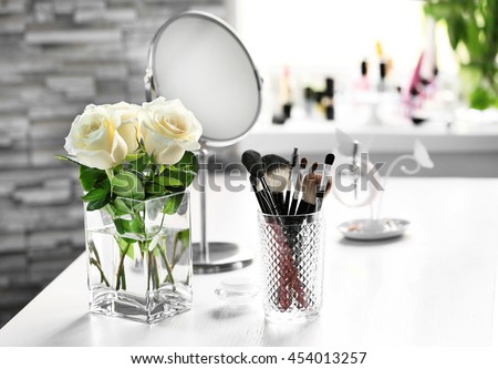 Cosmetic brushes with bouquet on light dressing table