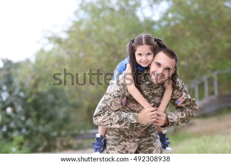 US army soldier with little daughter in park