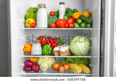 Open refrigerator full of vegetables and dairy products