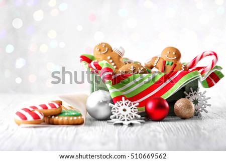 Box with tasty cookies and Christmas decor on light wooden table