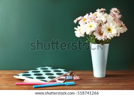 Copybooks and flowers on teacher\'s desk