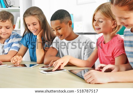 Schoolchildren sitting in classroom with mobile phones and tablet computers