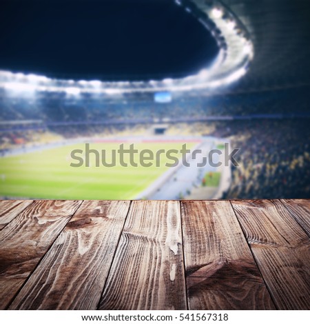 Wooden table against football stadium background