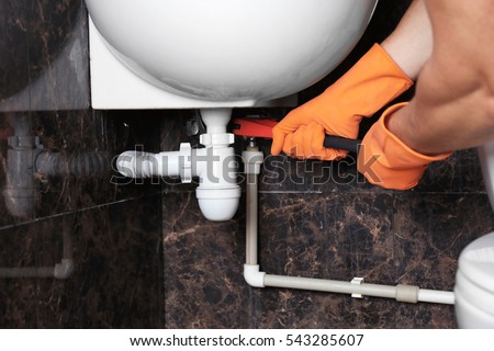 Plumber repairing sink pipe in bathroom