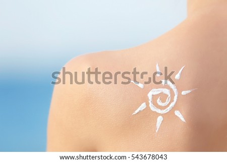 Woman with sun protective lotion in sun shape on shoulder