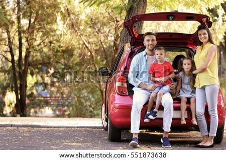 Family with kids sitting in car trunk