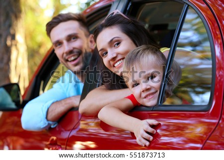 Happy family with son sitting in car on sunny day