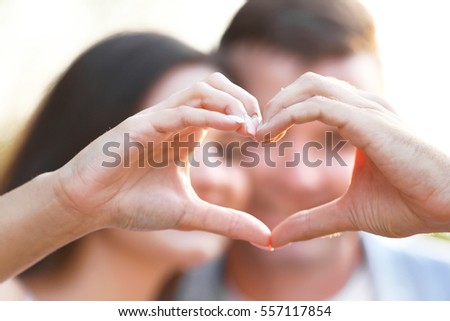 Young couple holding hands in shape of heart