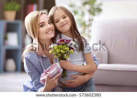 Beautiful young woman with present and bouquet of flowers from her daughter. Mother\'s day concept