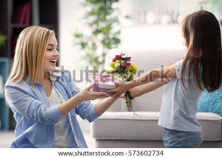 Little girl giving present to her mother at home. Mother\'s day concept