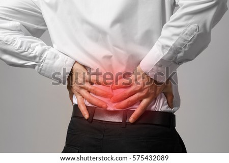 Man suffering from back ache on gray background. Health care concept