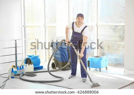 Dry cleaner\'s employee removing dirt from carpet in flat