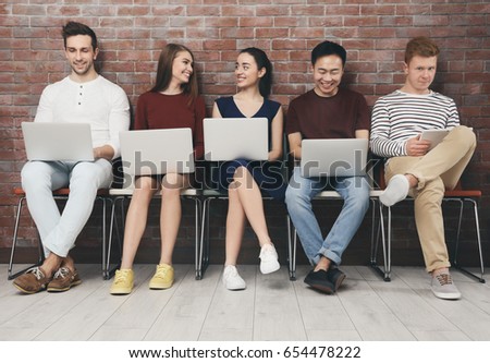 Young people with gadgets sitting on chairs
