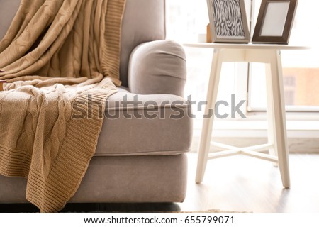 Cozy grey couch with plaid in modern room, close up