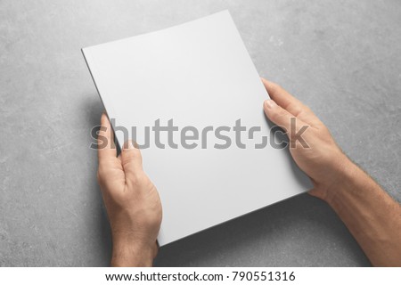 Man holding brochure with blank cover on grey background. Mock up for design
