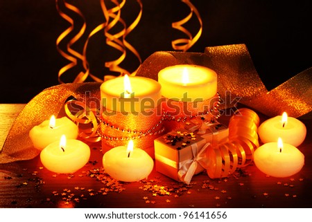 Beautiful candles, gifts and decor on wooden table on brown background