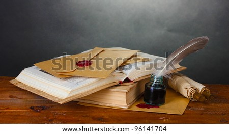 old books, scrolls, feather pen and inkwell on wooden table on grey background