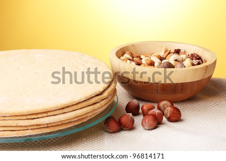 cakes for cake on glass stand and nuts on table on yellow background