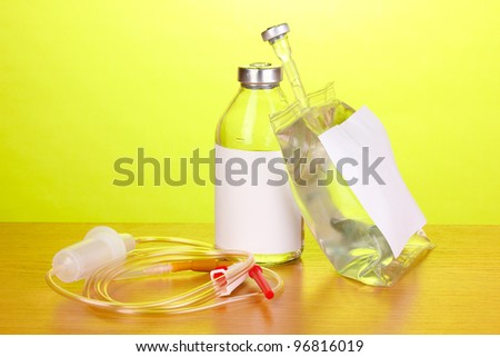 Bottle and bag of intravenous antibiotics and plastic infusion set on wooden table on green background